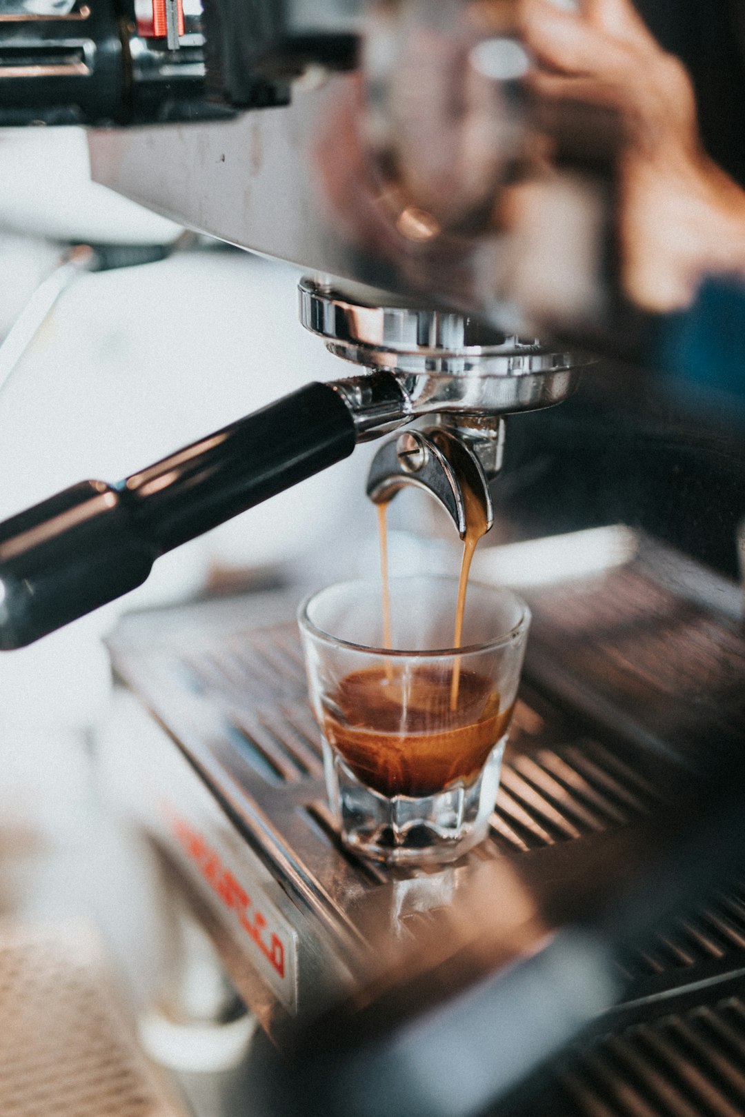 clear-drinking-glass-with-brown-liquid-on-silver-and-black-espresso-machine-dvuhntjxisg
