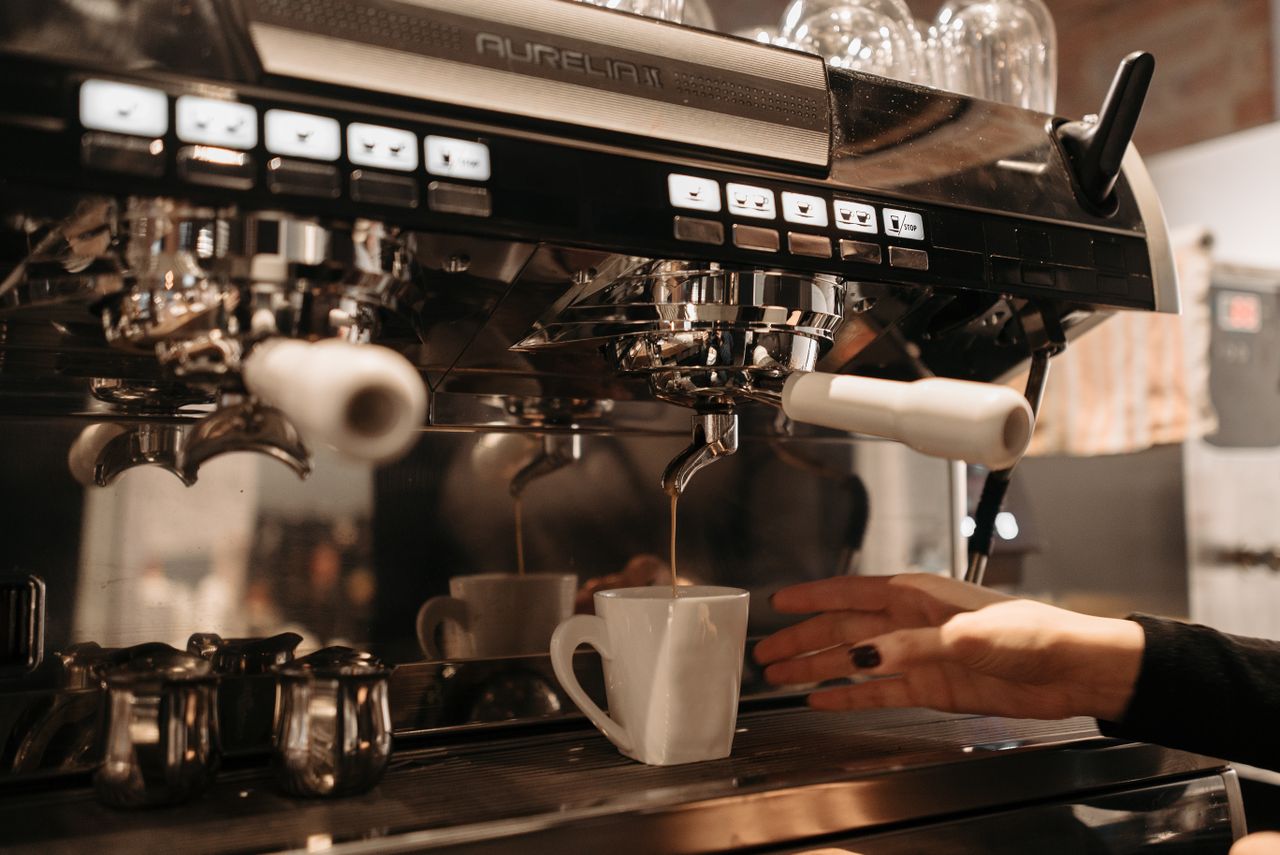 A barista preparing coffee with a commercial espresso machine, highlighting the brewing process in a cafe setting.